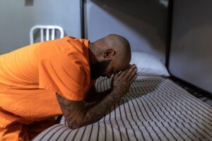 Male Prisoner Praying in Jail Cell